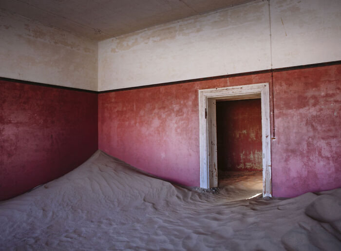 12. Sand piled deep against red and white walls like a buried time capsule