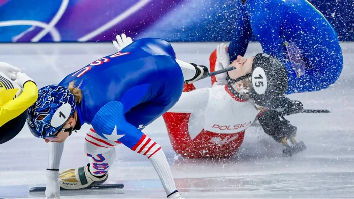 Speed skating arena scene, officials rush toward an injured athlete after incident